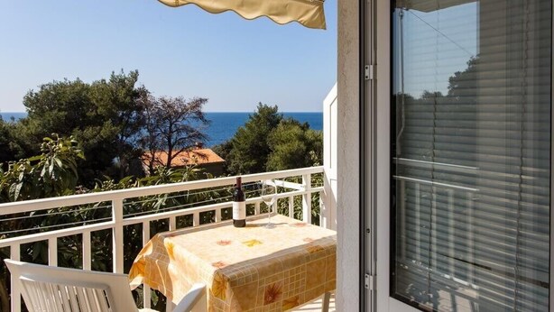 Un balcon avec une table, une bouteille de vin et un verre.