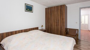 Ein Schlafzimmer mit einem Bett, einem Holzschrank, einem Stuhl und einem kleinen Tisch mit einer Lampe.