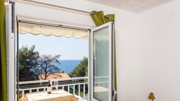Ein Balkon mit Tisch, Stühlen, einer Weinflasche und einer Lampe.