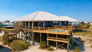 Een huis aan het strand met een houten terras, een zwembad en een zandstrand.
