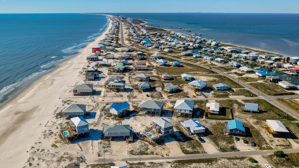 Luchtbeeld van een kustgebied met woonhuizen en toegang tot het strand.