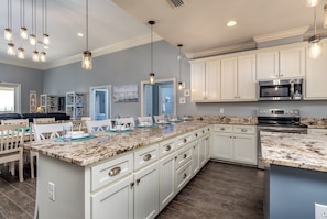 A spacious kitchen with white cabinetry, granite countertops, and stainless steel appliances.