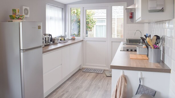 Una cocina moderna con armarios blancos, horno empotrado y ventana con vistas a zonas verdes.
