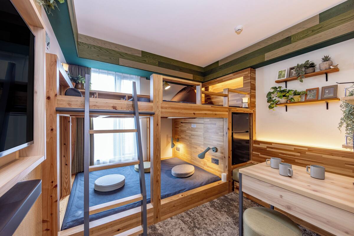 A compact, multi-level room with a bunk bed, a desk, and a small seating area.