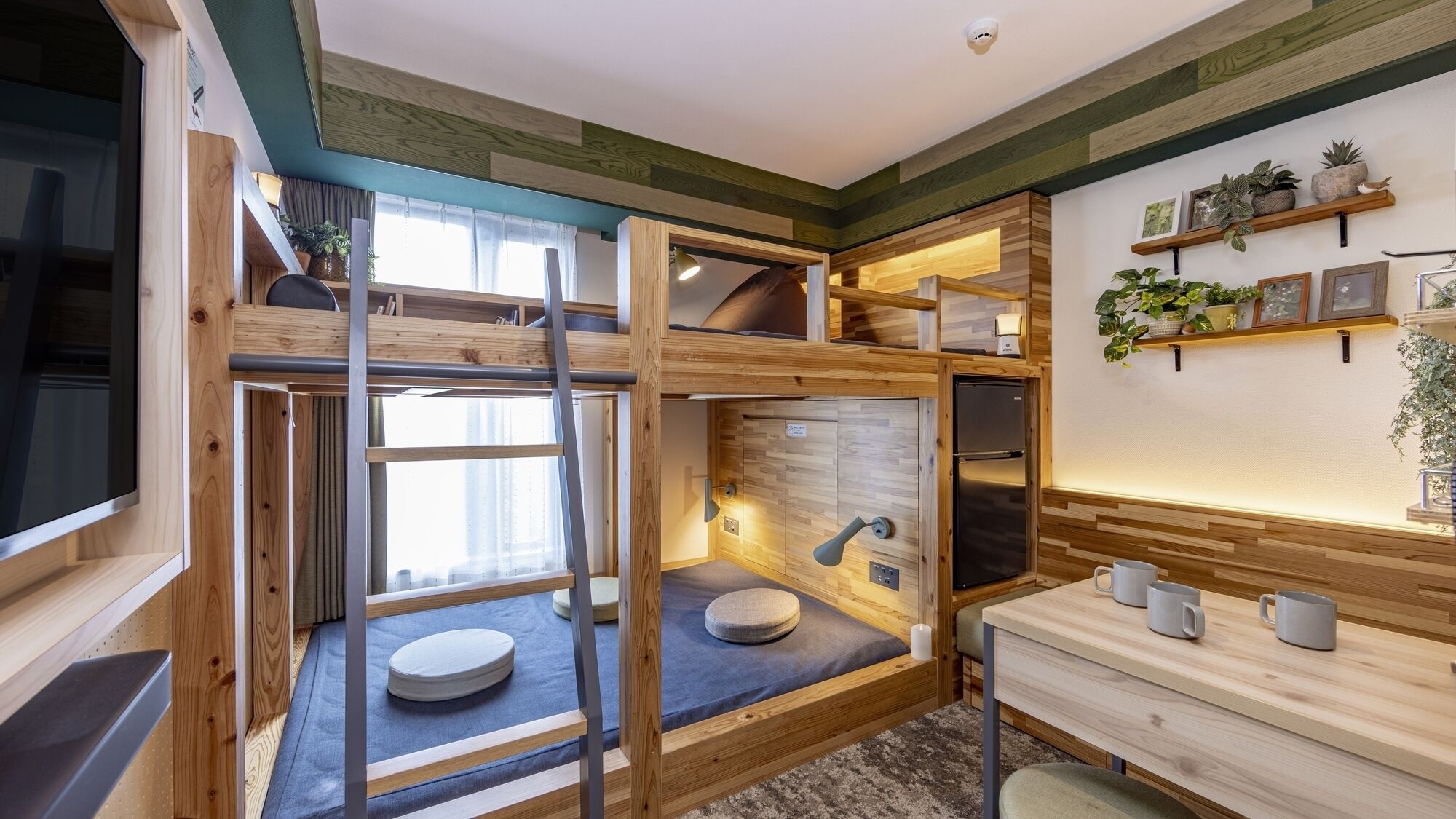 A compact, multi-level room with bunk beds, a small kitchenette, and a window providing natural light.