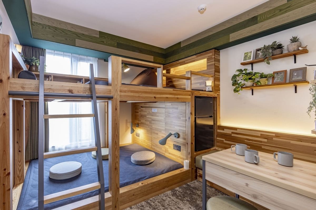 A compact, multi-level room with bunk beds, a small kitchenette, and a window providing natural light.