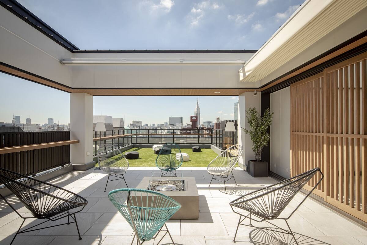 A rooftop terrace with a city view, modern seating, and a fire pit.