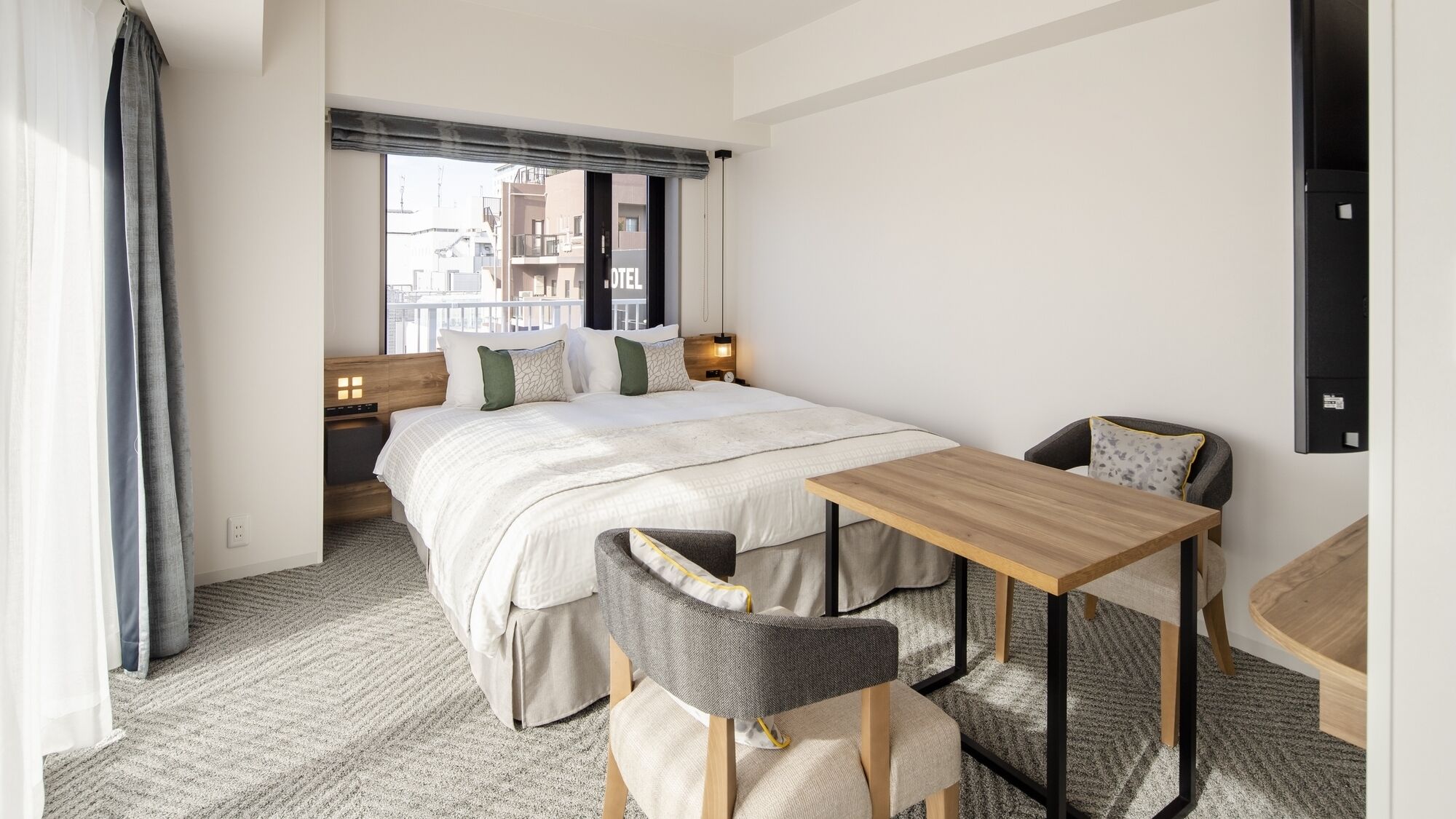 A hotel room with a bed, bedside tables, a desk, and a chair.