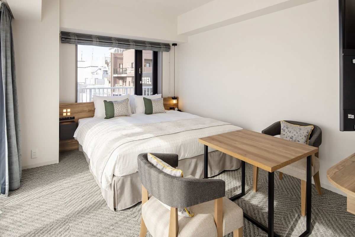 A hotel room with a bed, bedside tables, a desk, and a chair.