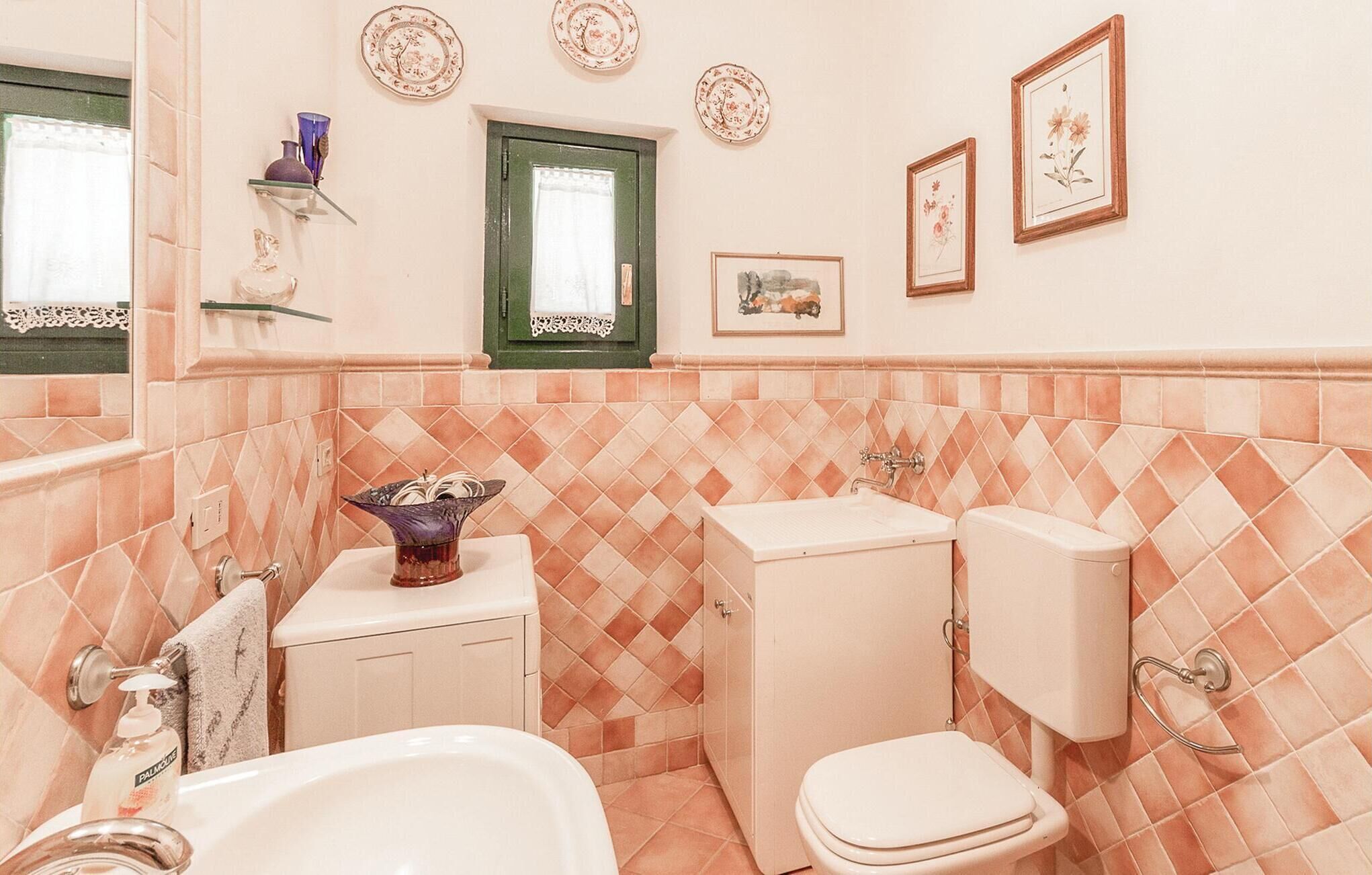 A bathroom with a toilet, sink, and bathtub. There are decorative plates on the wall and a vase on the sink.
