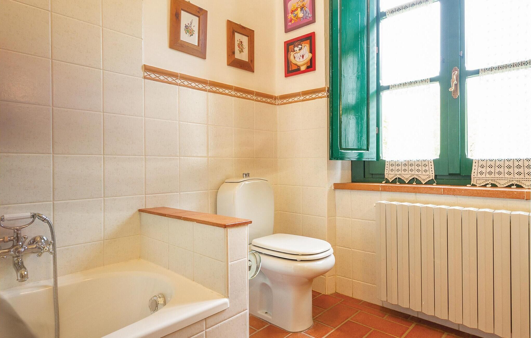 A bathroom with a bathtub, toilet, and a radiator.