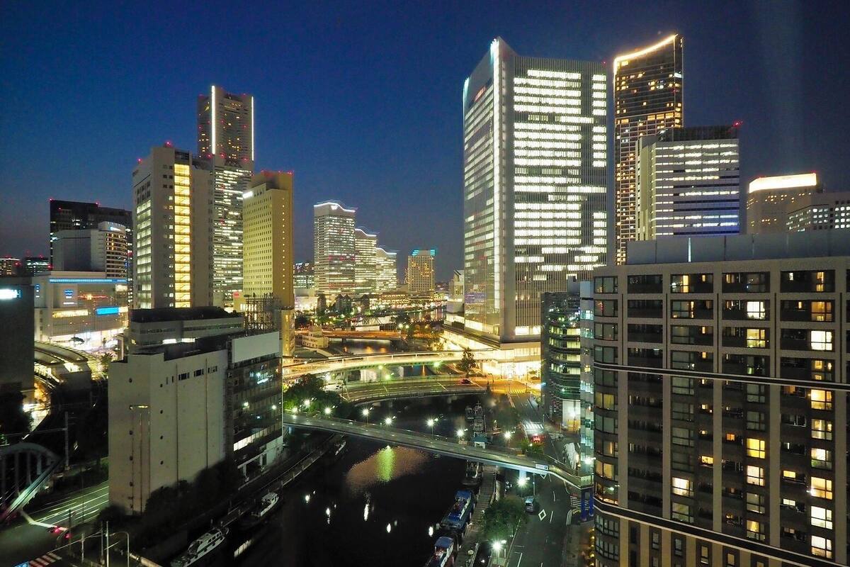 A cityscape at night with illuminated skyscrapers, a river, and a bridge.