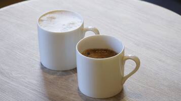 Two white ceramic cups on a round wooden table.