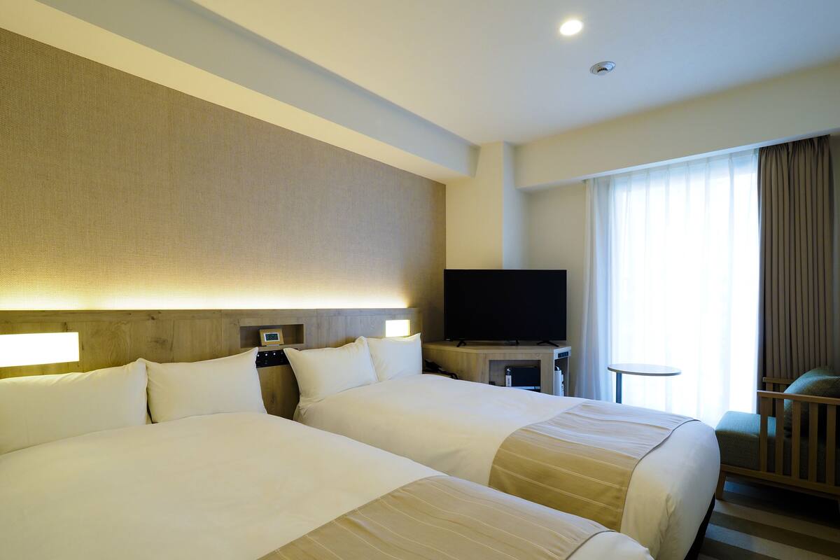 A hotel room with two beds, a television, and a small table.