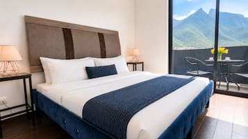 Une chambre d’hôtel avec un grand lit, deux tables de chevet et une vue sur les montagnes depuis un balcon.