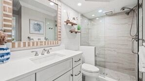 Een moderne badkamer met een grote spiegel, twee wastafels, een toilet en een douche.