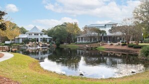 Un hotel junto al lago con un edificio grande, un muelle y un estanque con patos.