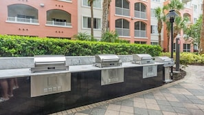 Barbecue all'aperto su una mensola in pietra, con un edificio sullo sfondo.