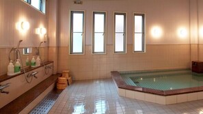 A bathroom with a bathtub, a shower, and a toilet. There are three windows providing natural light. - Shirota Hotel (Maebashi)