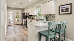 Una cocina moderna con armarios blancos, una isla grande con taburetes y un salpicadero de azulejos.