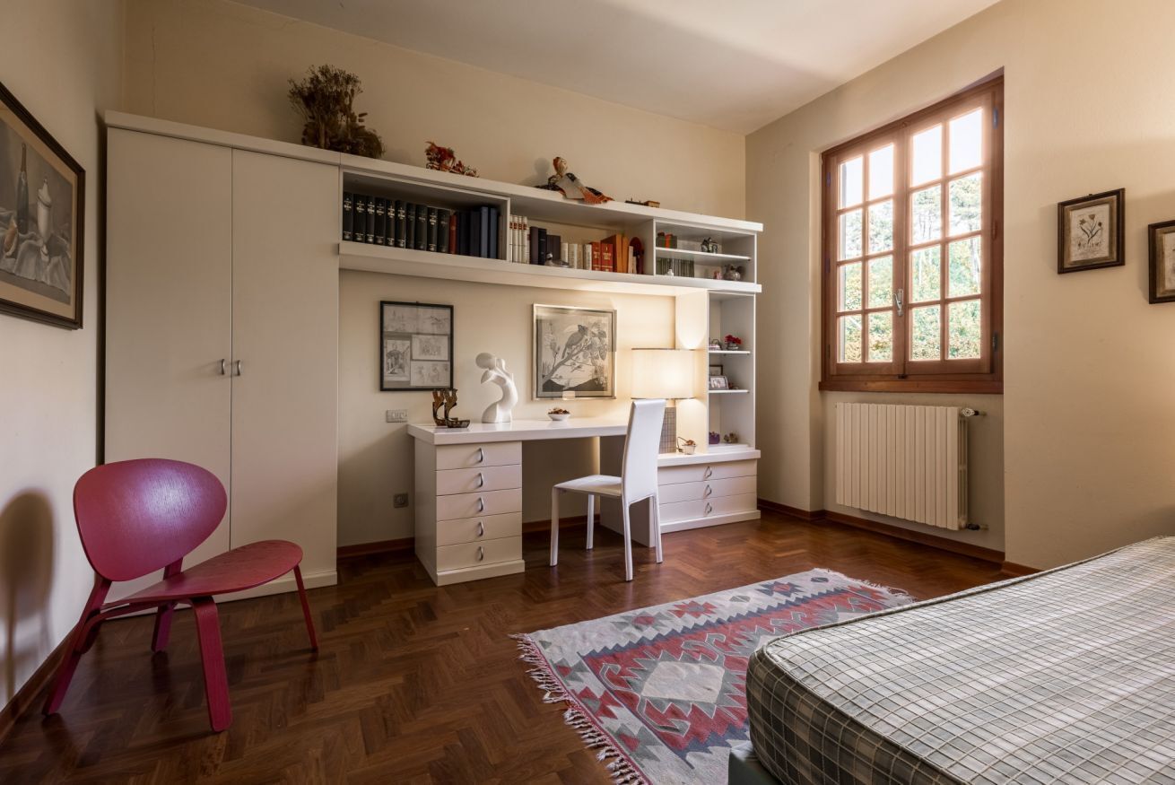 Une chambre à coucher avec un lit, un bureau, une chaise, un radiateur et une fenêtre.