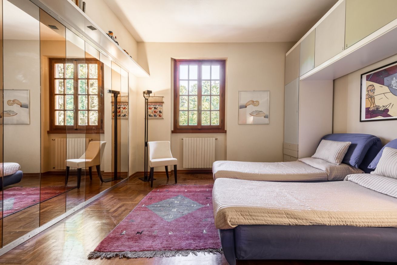 A bedroom with a bed, two chairs, a radiator, and a window.