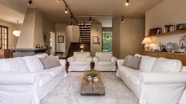 A modern living room with white sofas, a coffee table, and a staircase leading to another level. - Villa la Bruscola by MMega (Barberino di Mugello)