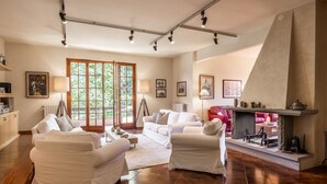 A spacious living room with a fireplace, white furniture, and large windows. - Villa la Bruscola by MMega (Barberino di Mugello)
