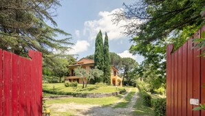 A pathway leading to a house with a red fence on one side and a stone wall on the other. - Villa la Bruscola by MMega (Barberino di Mugello)