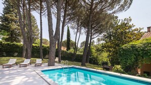 A swimming pool with lounge chairs, surrounded by tall trees and greenery. - Villa la Bruscola by MMega (Barberino di Mugello)