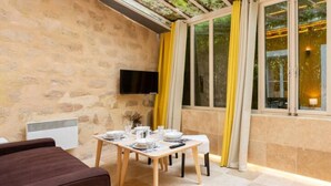 A dining area with a stone wall, a TV mounted on the wall, and a table set for four.