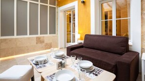 A dining area with a brown sofa, a table set with plates, glasses, and cutlery.