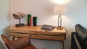 Uma mesa de madeira com uma luminária, livros e uma poltrona de couro.