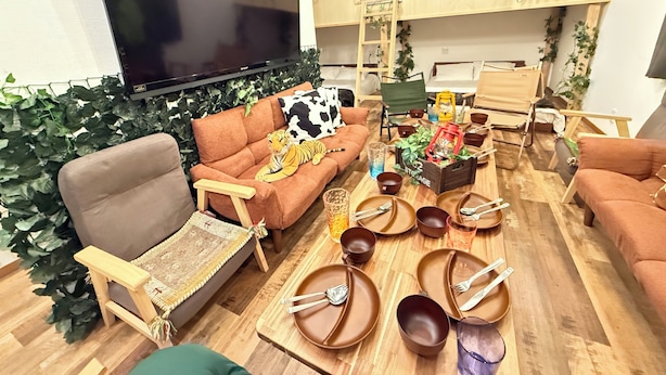 A living room with a sofa, a TV, a dining table with plates and cutlery, and a wooden coffee table. - Eternity APARTMENT HOTEL SHINAGAWA (Tokyo)