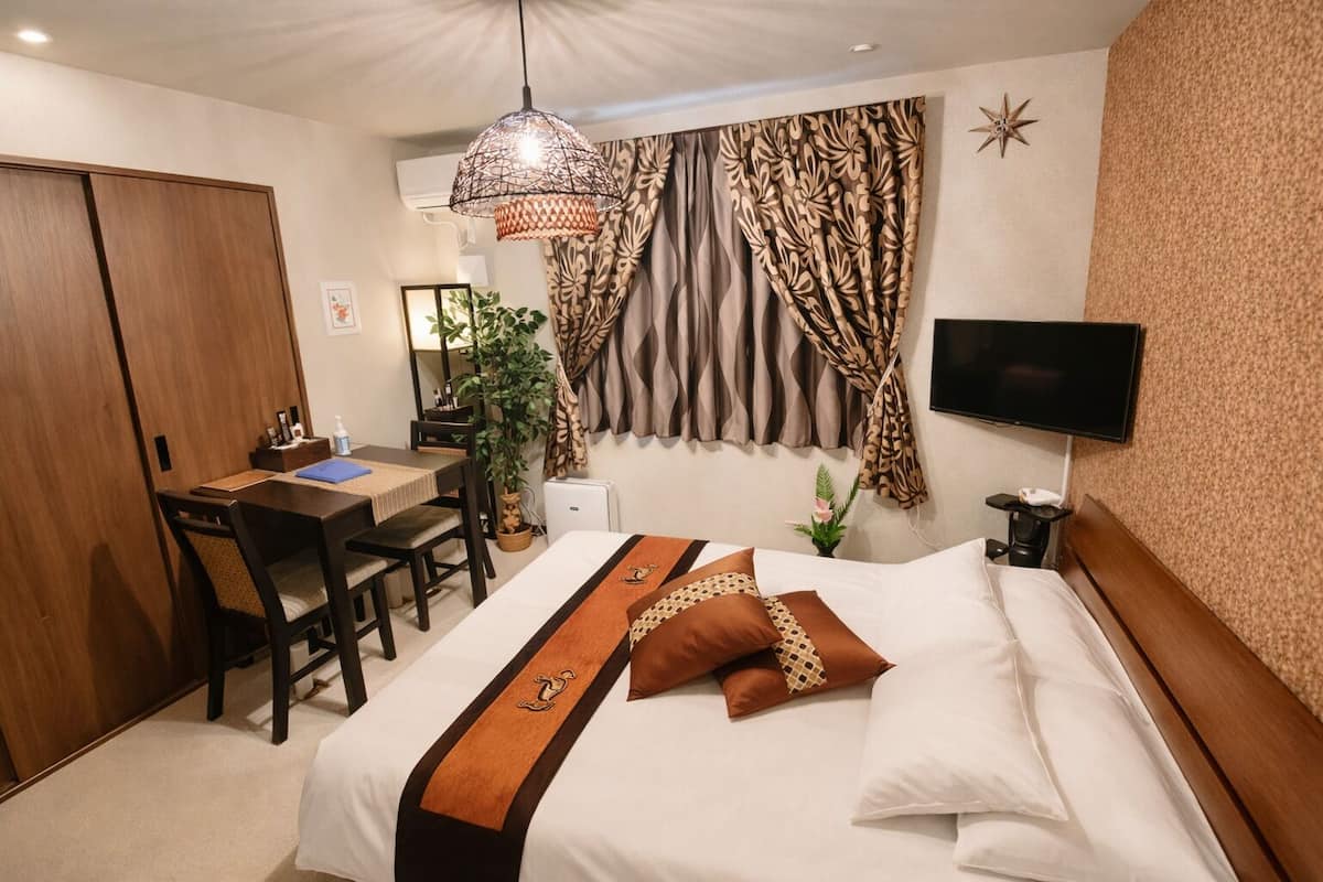 A hotel room with a bed, desk, chair, and a television.