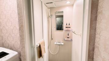 A small, well-lit bathroom with a shower, a towel rack, and a mirror.