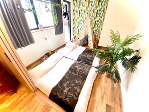 A compact room with a bed, a small table, a potted plant, and a window with curtains. - Eternity APARTMENT HOTEL SHINAGAWA (Tokyo)