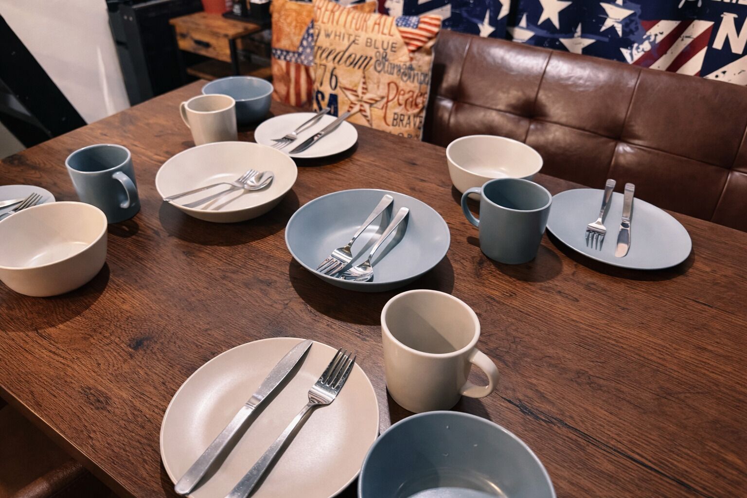 Een eettafel gedekt met borden, kommen en bestek.