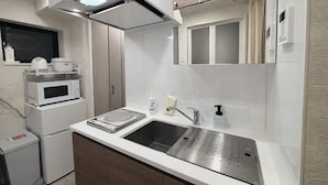 A compact kitchen with a microwave, sink, and storage cabinets. - Eternity APARTMENT HOTEL SHINAGAWA (Tokyo)