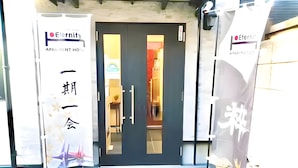 A hotel entrance with a dark-colored door, two banners on either side, and a blue tiled floor. - Eternity APARTMENT HOTEL SHINAGAWA (Tokyo)