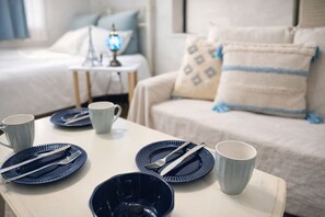 A neatly arranged breakfast table with plates, cutlery, and cups, set against a backdrop of a bed and a nightstand with a lamp. - Eternity APARTMENT HOTEL SHINAGAWA (Tokyo)