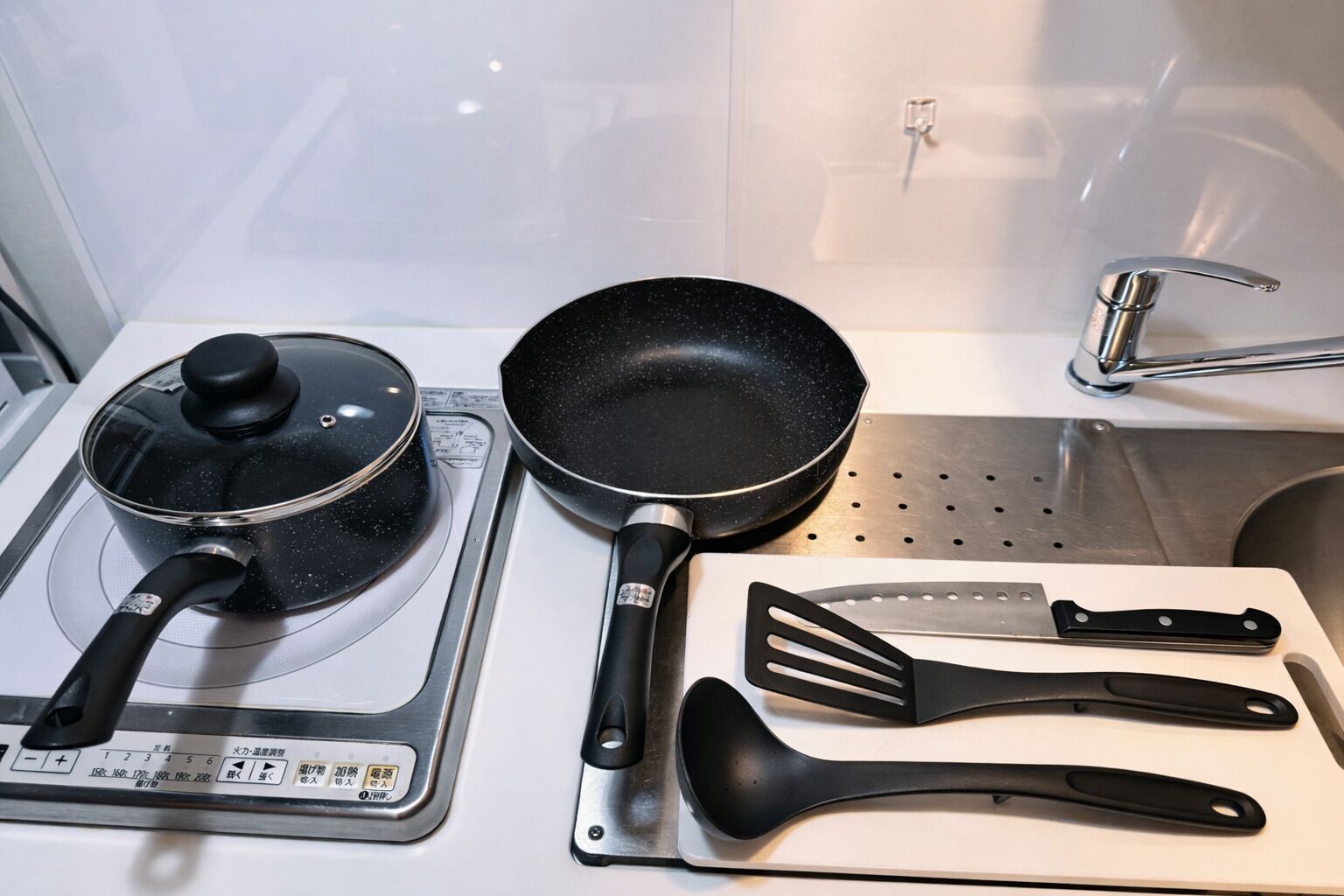 A kitchen with a stove, a frying pan, and a cutting board with spatulas.