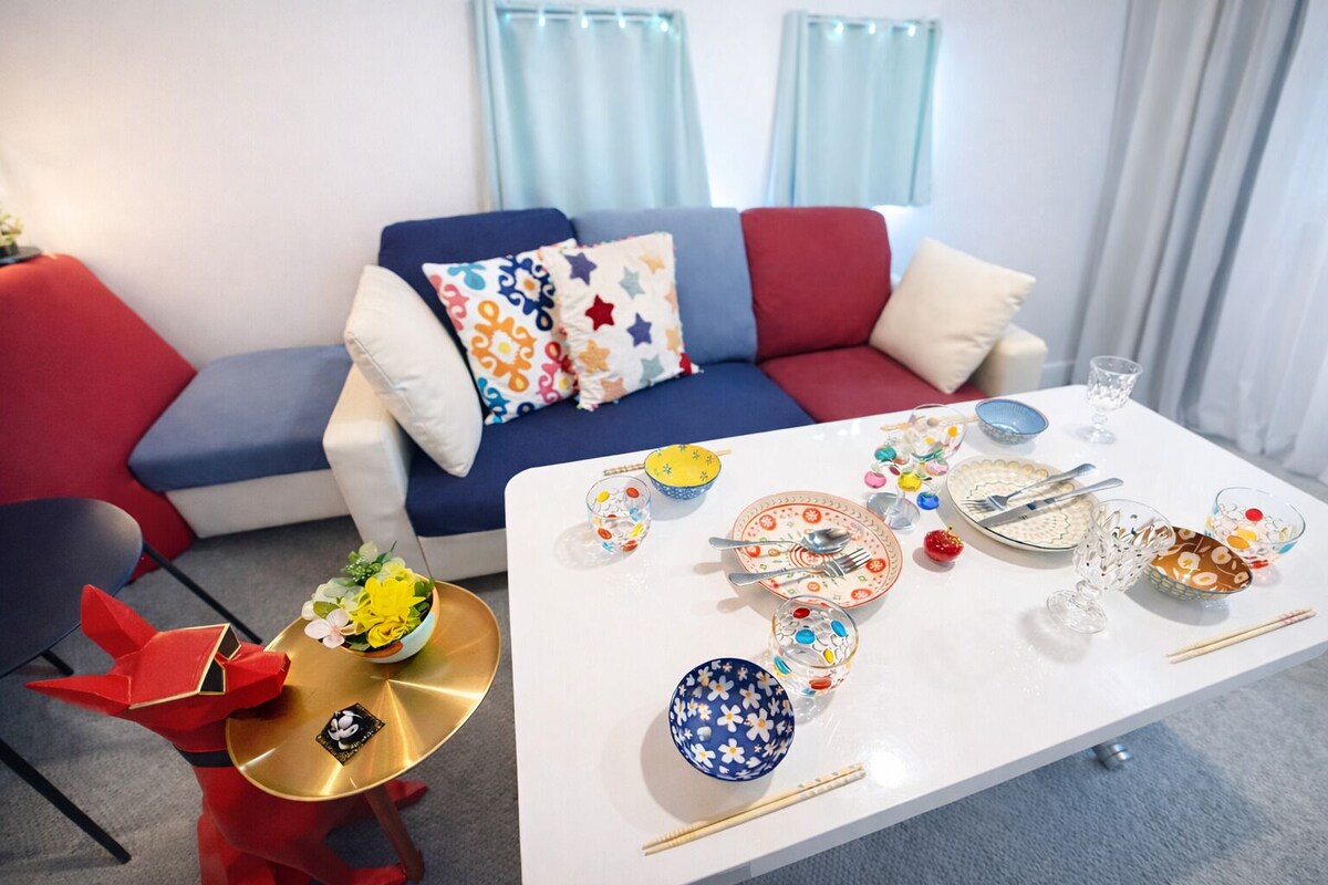 A modern living room with a sofa, a coffee table set for dining, and a decorative plant.