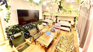 A cozy living room with a flat-screen TV, comfortable seating, and hanging plants. - Eternity APARTMENT HOTEL SHINAGAWA (Tokyo)