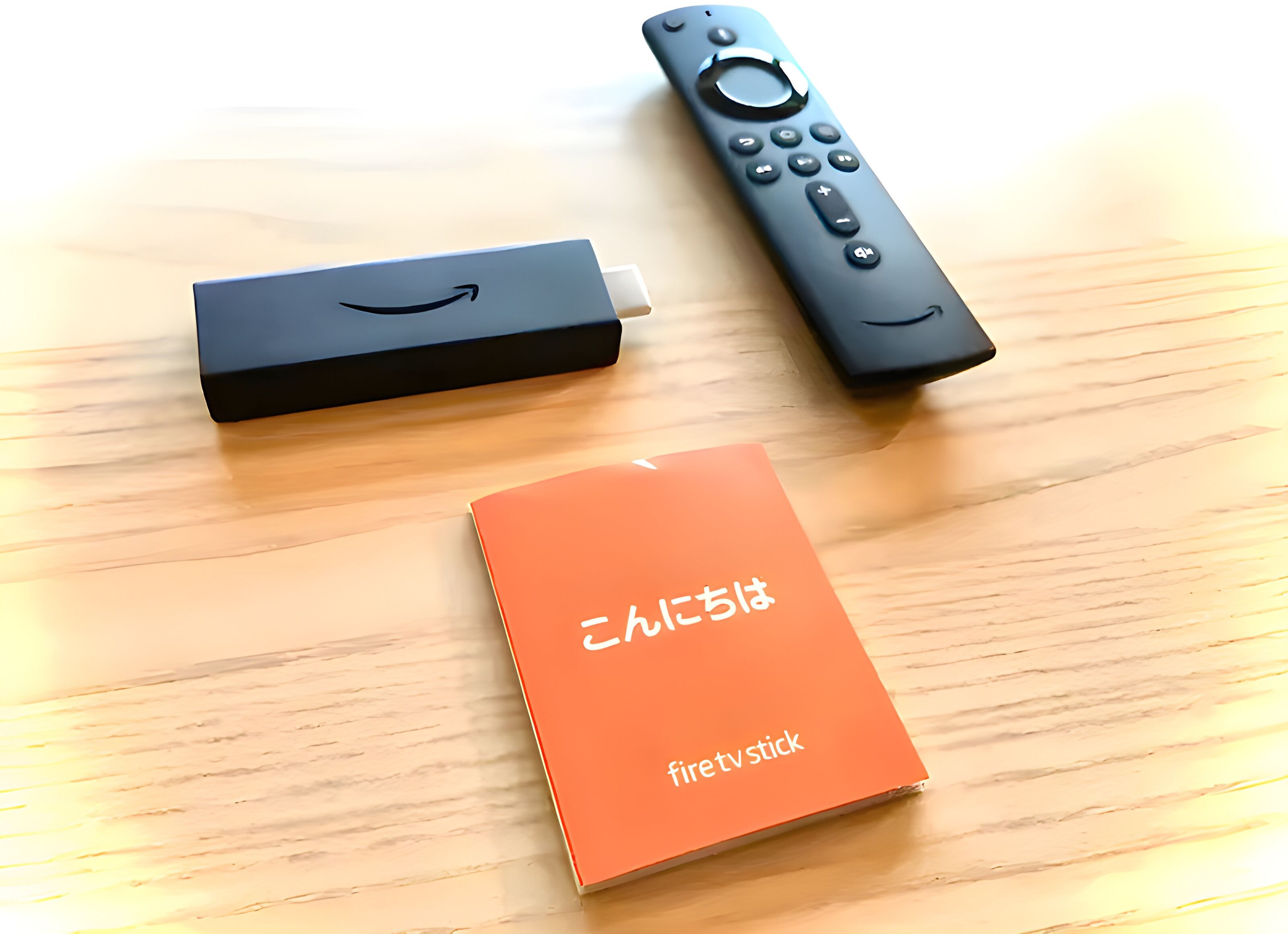 A wooden table with an orange box labeled "firetv stick" and two electronic devices, one black and one remote control.