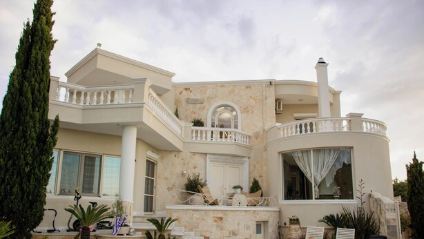 Una casa grande de varios niveles con balcón, escalera y zona de piscina.