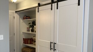 A hallway with a sliding closet door, a shelf with books and a plant, and a basket on the floor. - The Perfect Lie in Pinehurst! A golfer's paradise! (Pinehurst)