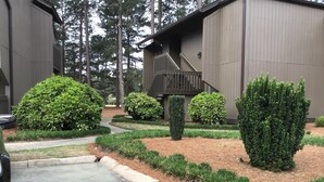 A residential building with a driveway, a wooden staircase, and well-maintained landscaping including bushes and a hedge. - The Perfect Lie in Pinehurst! A golfer's paradise! (Pinehurst)