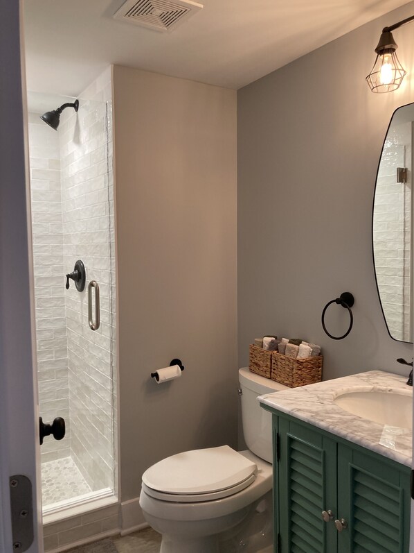 A bathroom with a shower, toilet, and vanity.