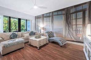 A spacious living room with a large window, a ceiling fan, and a view of the outdoors.